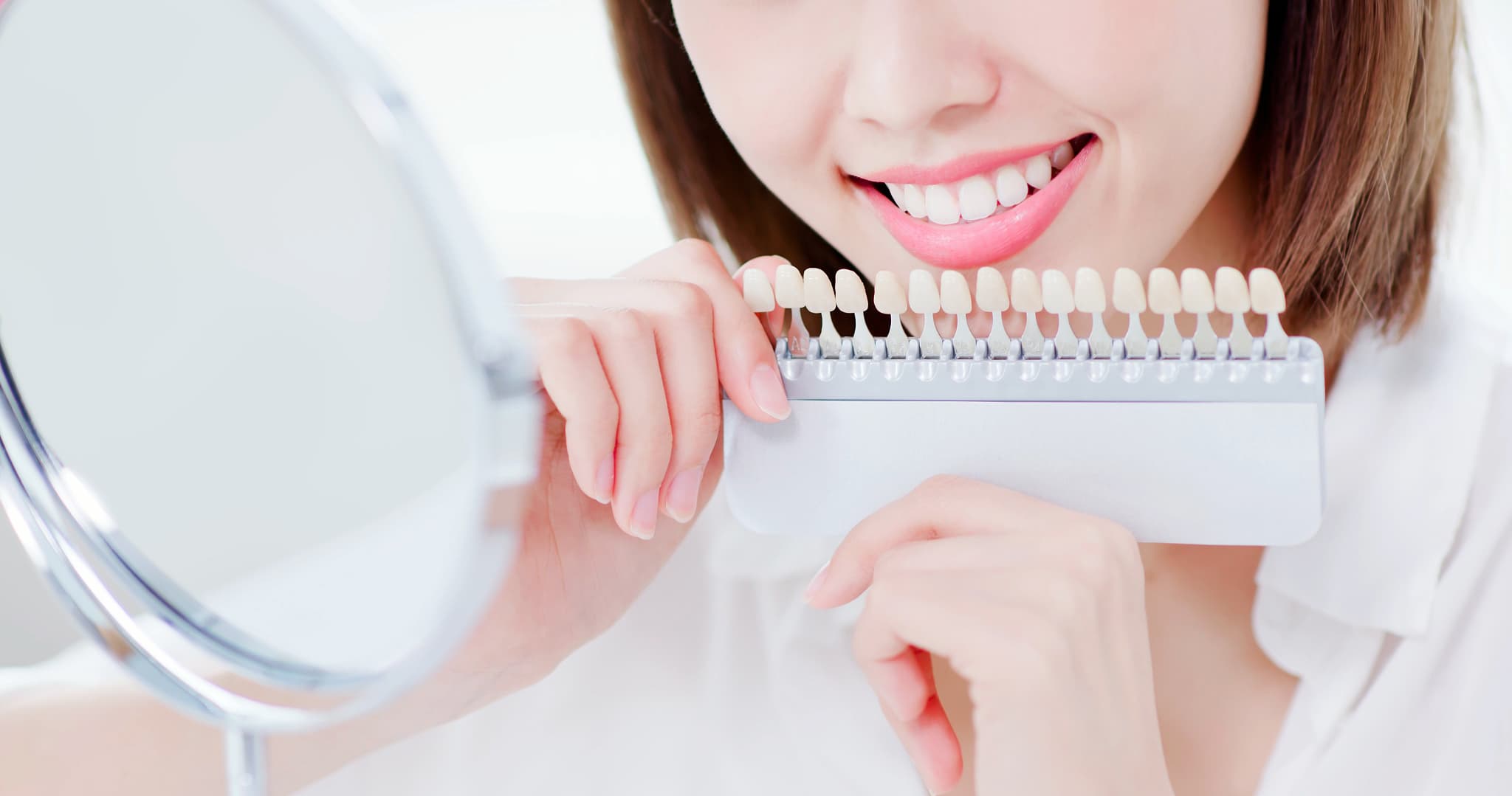 ホワイトニングをした歯の色をシェードガイドで確認する女性