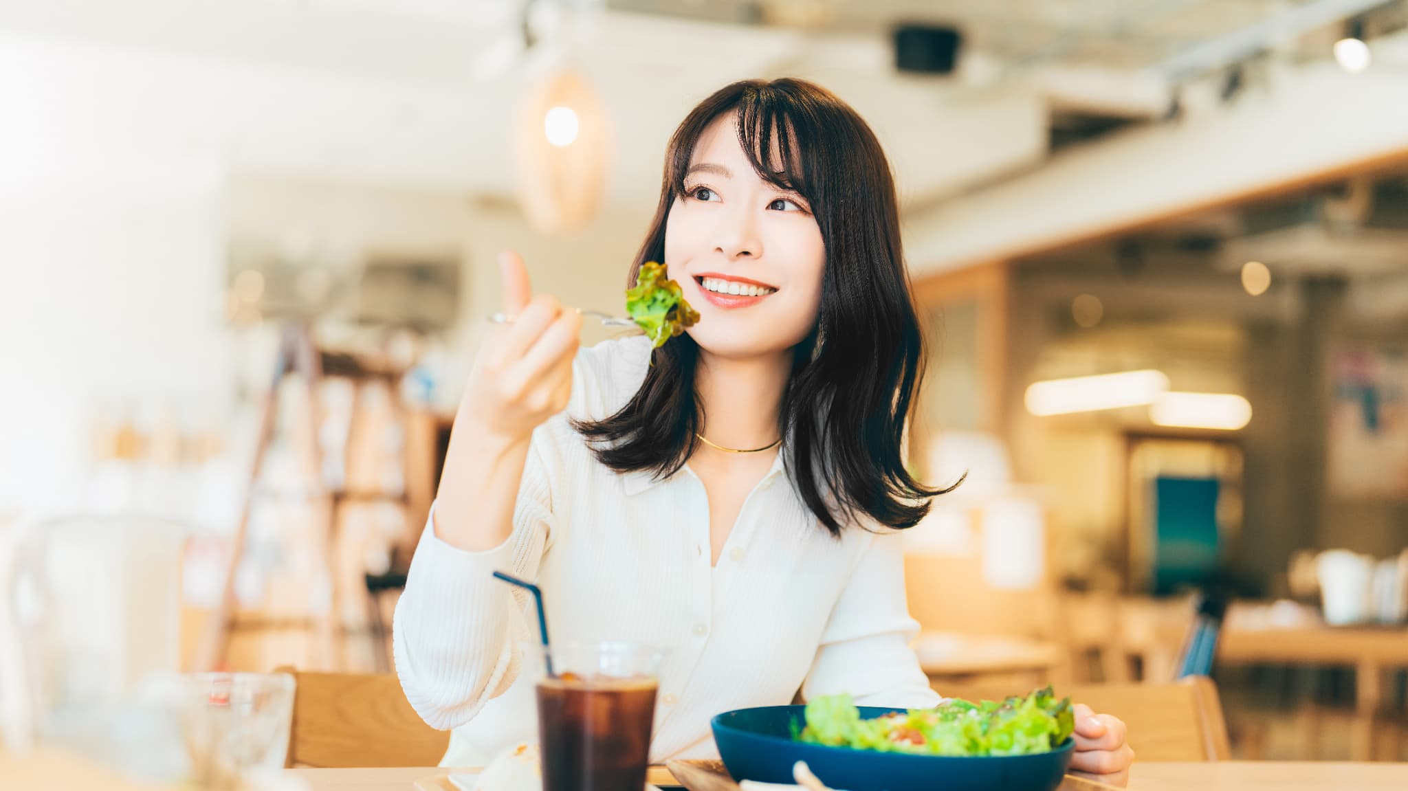 カフェで食事を楽しむインビザライン矯正中の女性