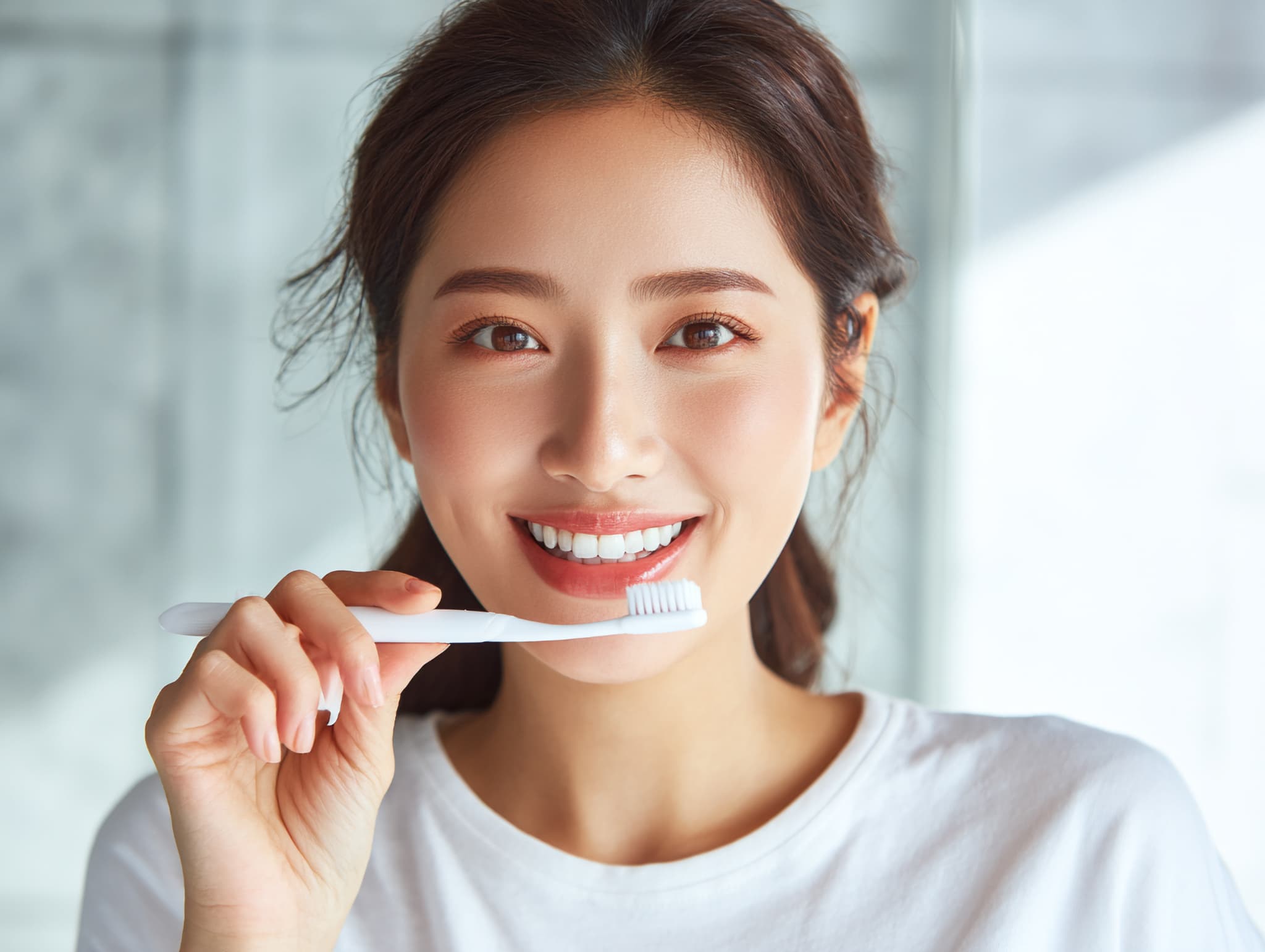 ホワイトニング後の白い歯を維持するため丁寧に歯磨きをする女性