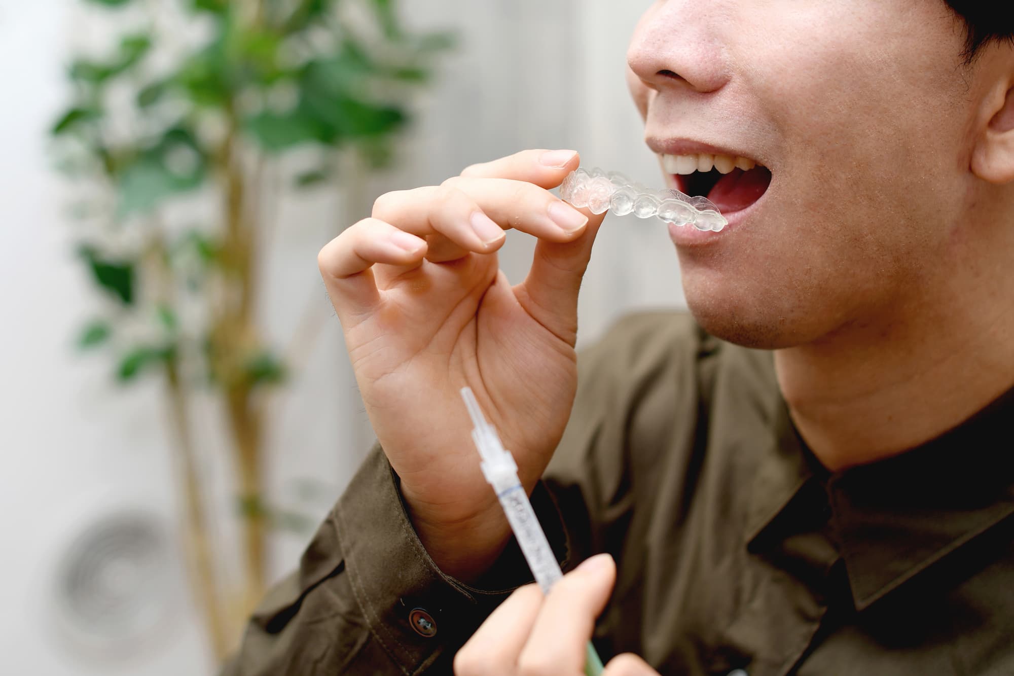 シリンジで薬剤を充填したマウスピースを装着しようとしている男性