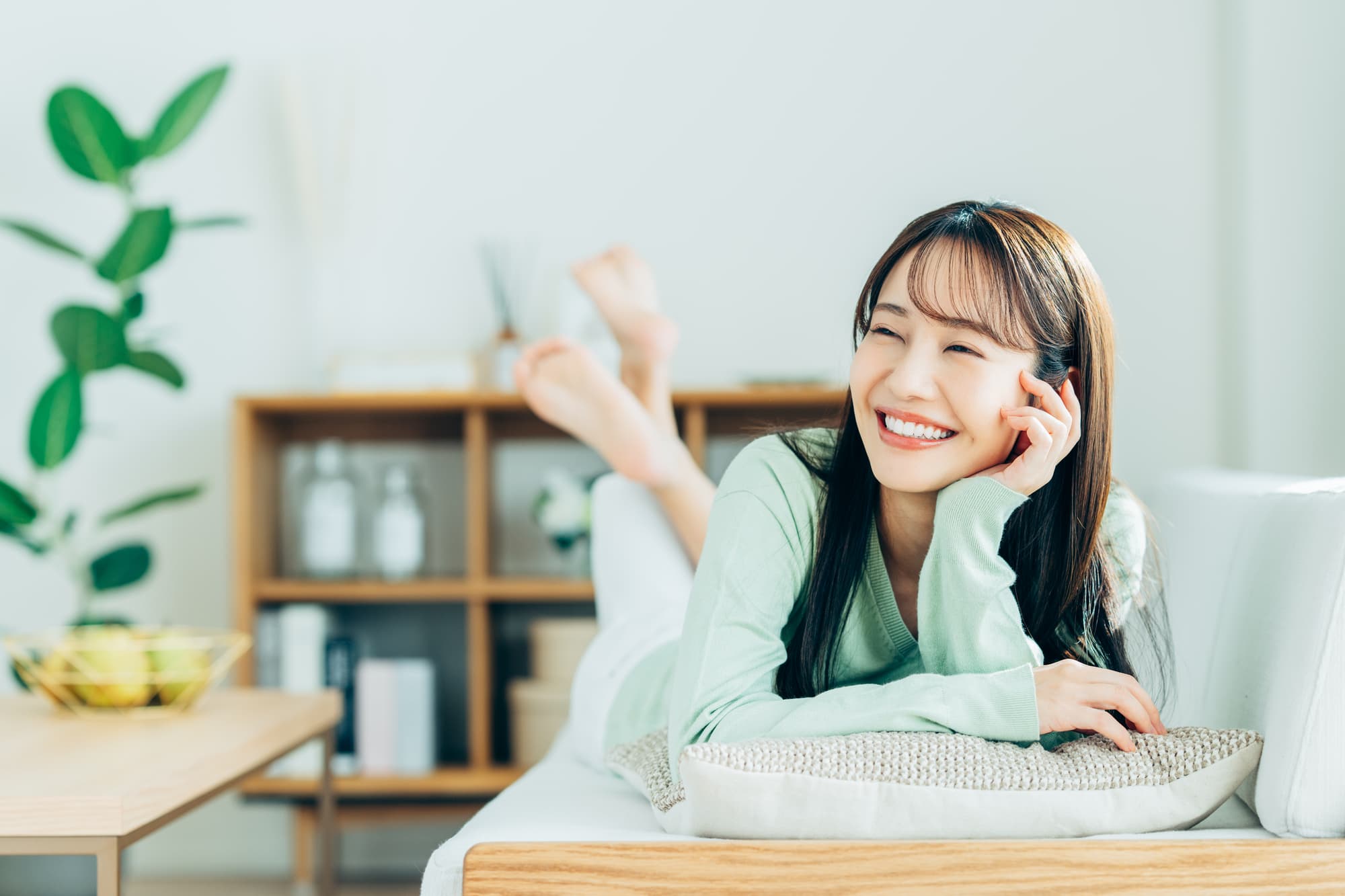 部屋で寛いでいるインビザラインで整った歯並びになった笑顔の女性